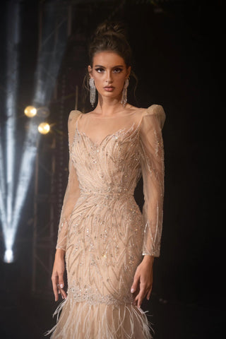 Woman in a beaded gown with feather trim.