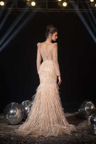 Woman in a long, feathered gown, standing near disco balls.