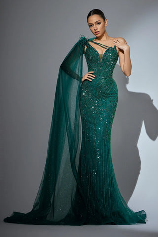 Woman in a green sequined evening gown with a cape.