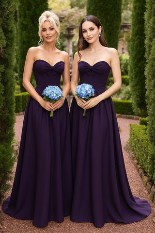 Two women in purple strapless gowns holding bouquets.