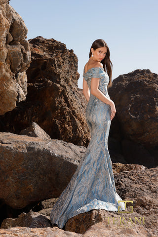 Denim off-shoulder gown on model near rocks