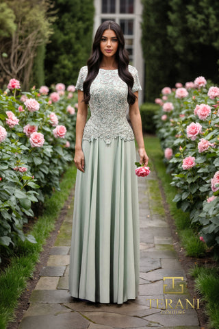 Woman in green gown, holding a pink rose, walking path.