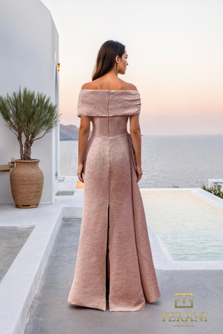 Woman in off-shoulder rose gown by the sea.