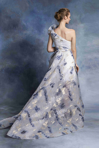 Woman in a white and blue floral one-shoulder gown.