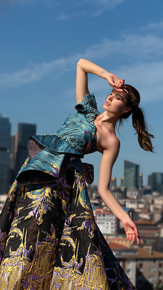 Woman in ornate dress posing outdoors.