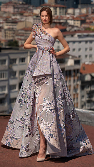 Woman in a formal gown with floral detail, standing on a rooftop.
