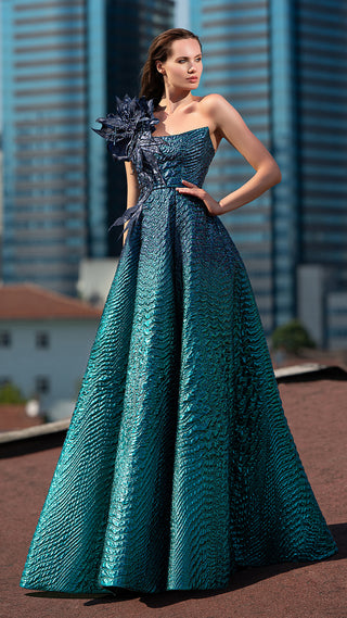 Woman in teal gown with floral shoulder detail.