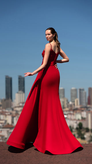 Woman in red gown posing outdoors.