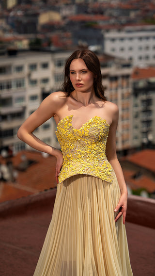 Woman in yellow strapless gown on rooftop.
