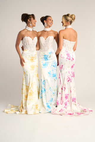 Three women in yellow, blue, and pink floral gowns
