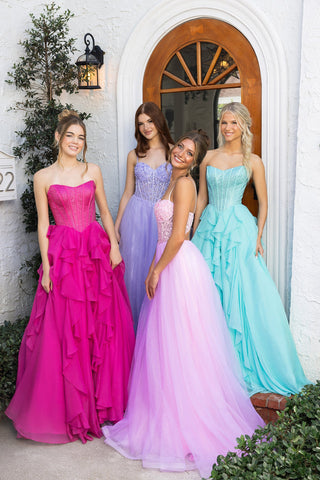 Four women in formal gowns posing by an arched doorway.