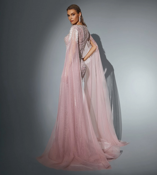 Woman in a pink, flowing gown with cape, posing.