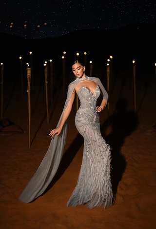 Woman in a long, gray evening gown with cape.