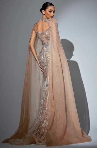 Woman in a sparkling gown with a flowing cape.