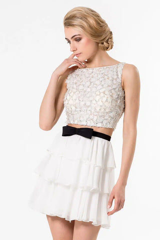 Woman in white crop top and tiered skirt with black bow.