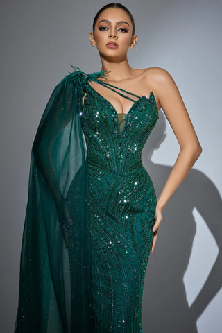 Woman in a green sequined gown with a cape.