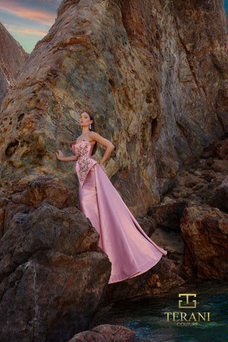 Rose-colored dress on woman by rocks.