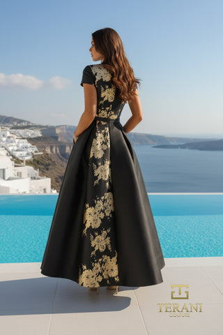 Woman in black floral Terani dress overlooking water