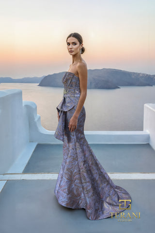 Blue and gold patterned formal gown on woman, ocean background