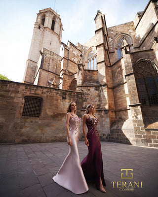 Two women in gowns in front of a stone building.