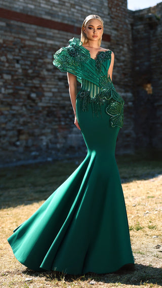 Woman in green formal gown posing outdoors.