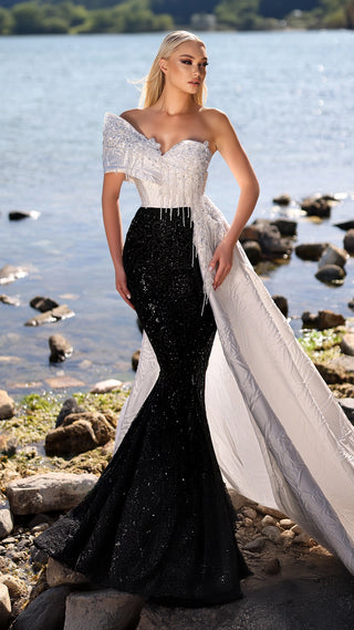 Woman in black and white formal gown by water.
