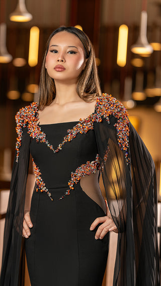 Woman in black gown with beaded shoulder detail.