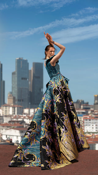 Woman in patterned gown posing outdoors.