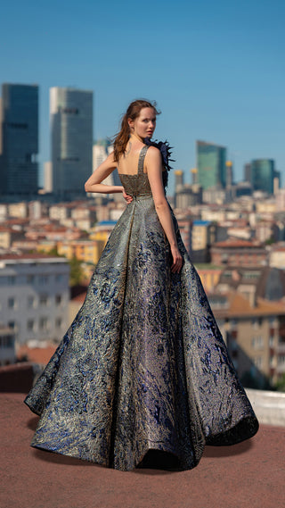 Woman in a long, patterned gown with city skyline background.