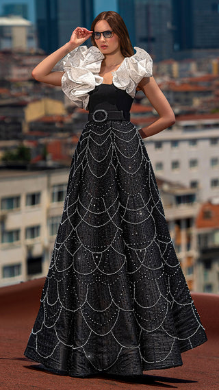 Woman in black and white gown, city background.