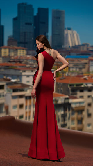 Woman in red gown on rooftop, cityscape background.