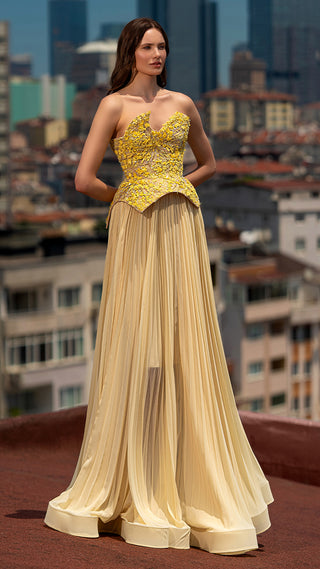 Woman in yellow strapless gown, city background.
