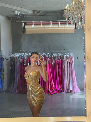 Woman in gold sequin dress taking mirror selfie