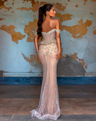 Woman in a formal beaded gown, standing with back to camera.