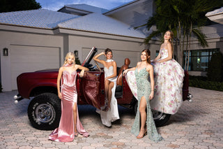 Women in formal gowns posing by vintage red truck