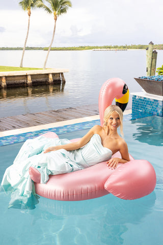 Woman in light blue dress on pink flamingo float.