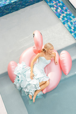 Woman in light blue dress on pink flamingo floatie