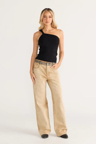 Cara in black one-shoulder top and tan jeans