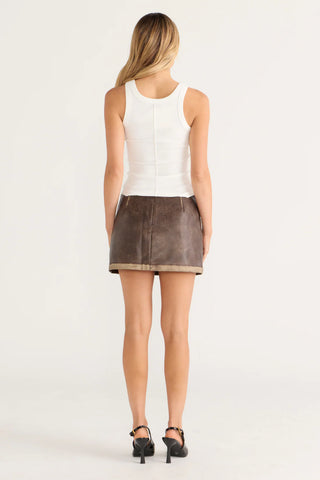 Woman in white tank top and brown skirt