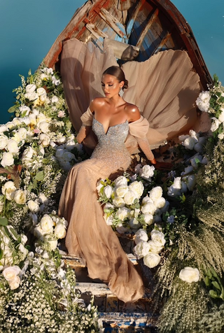 Woman in formal gown in a boat surrounded by flowers.