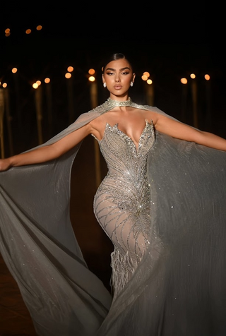 Woman in a sparkling silver gown with cape.