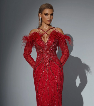 Woman in red beaded gown with feather details.
