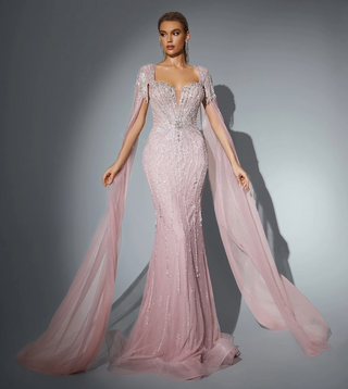 Woman in a long, pink, beaded gown with flowing sleeves.